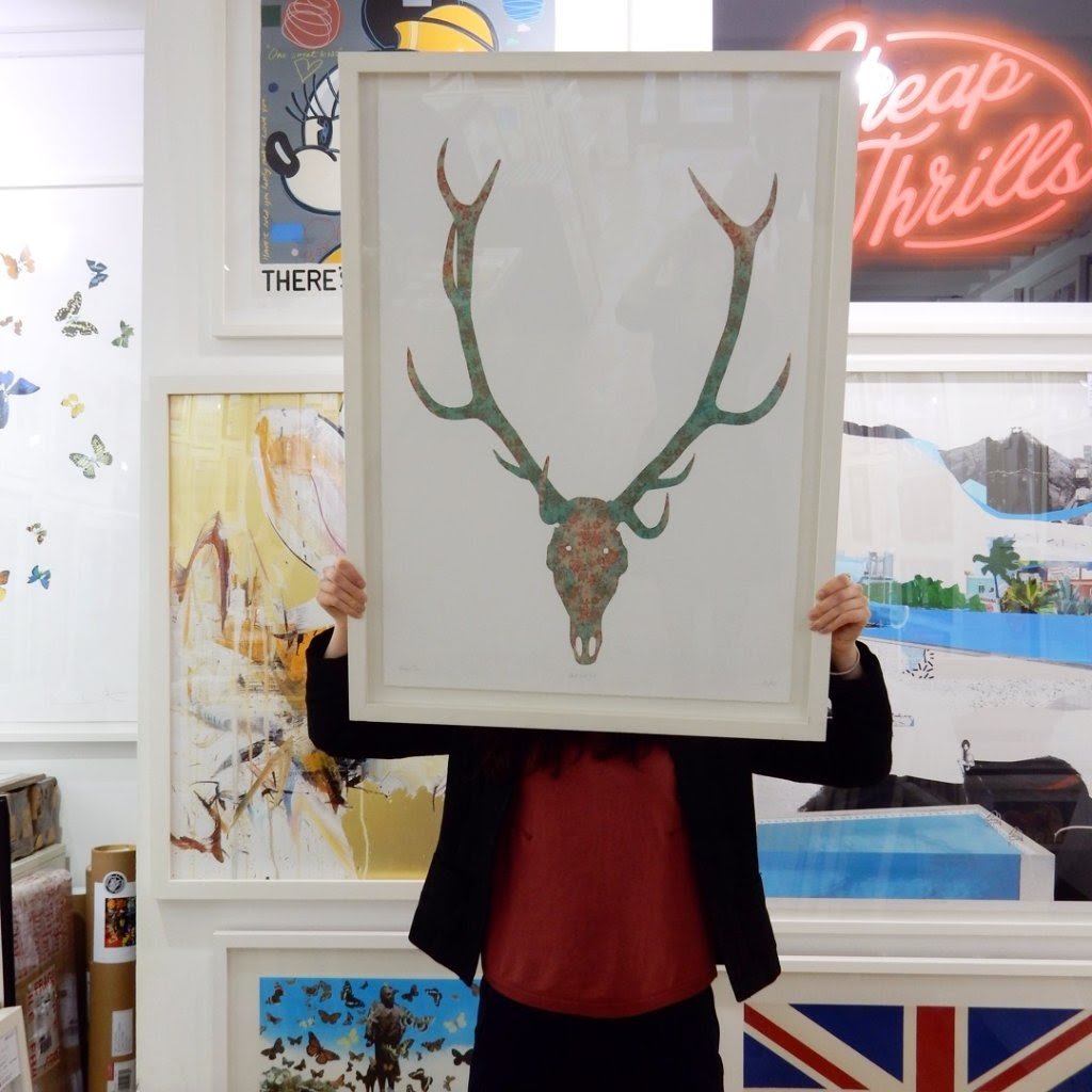 The floral stag skull print framed and held aloft at the gallery